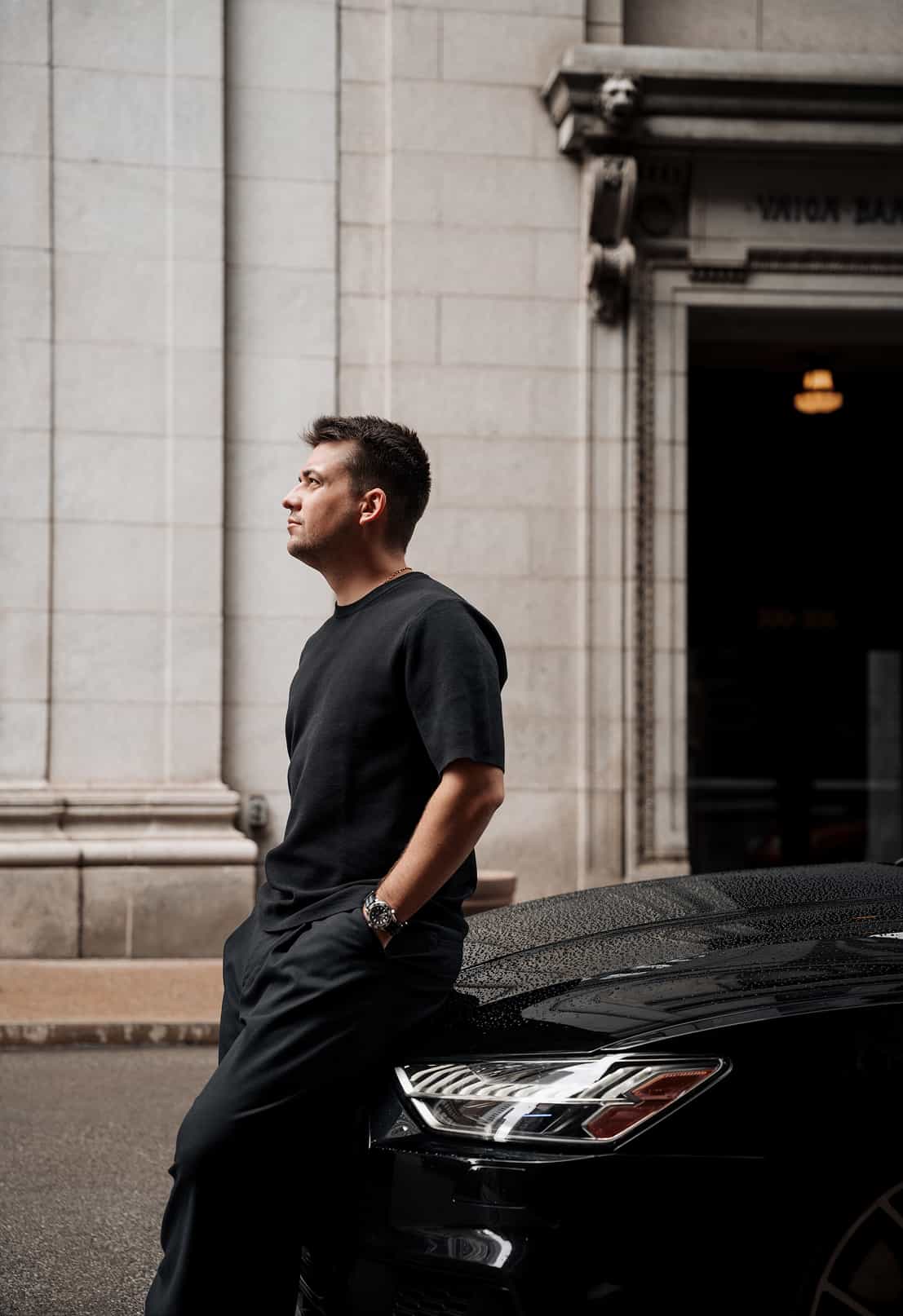 Portrait of Pittsburgh photographer Ivan Cheb standing beside a black luxury car in downtown Pittsburgh