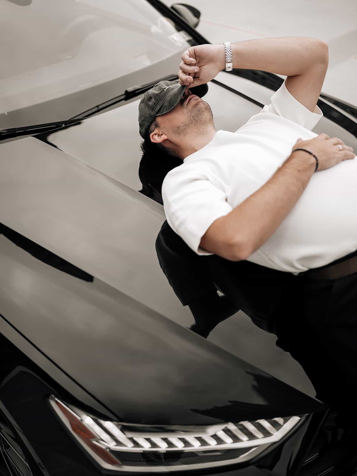 Editorial portrait of photographer Ivan Cheb leaning on a luxury car during a lifestyle photoshoot