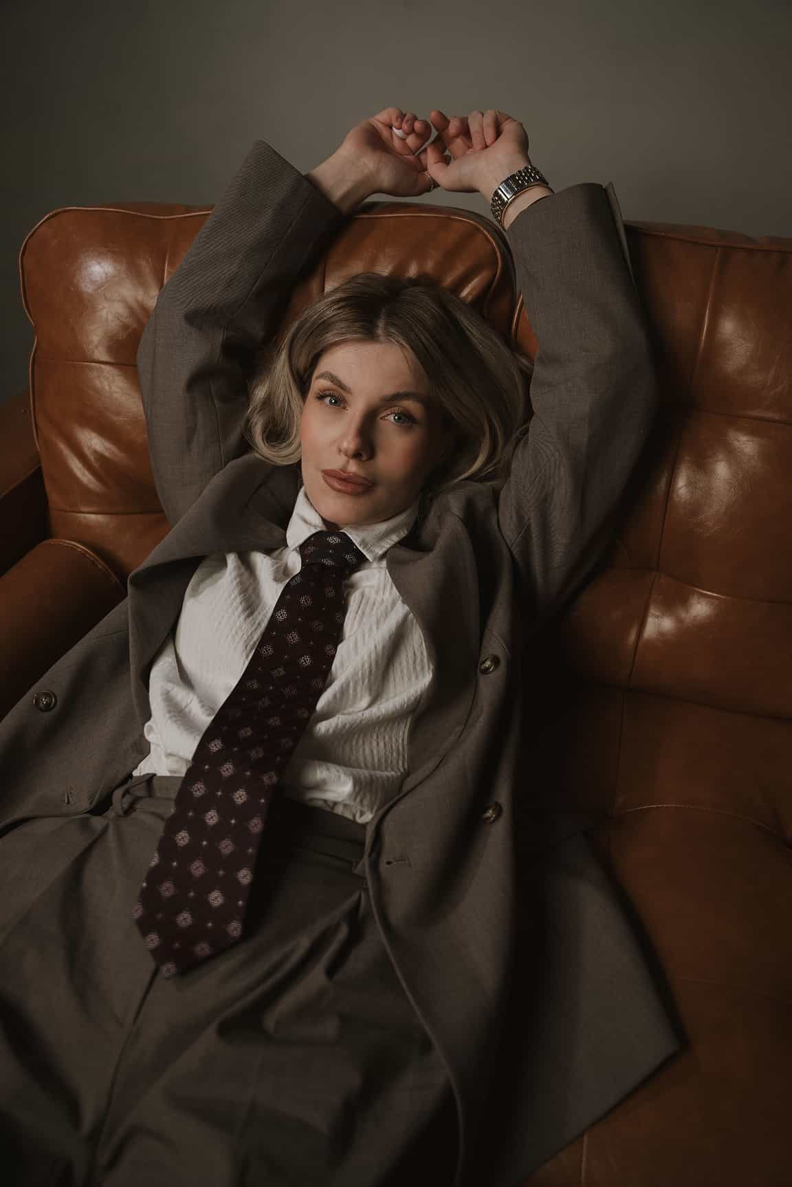 Studio fashion portrait of a woman reclining on a leather chair
