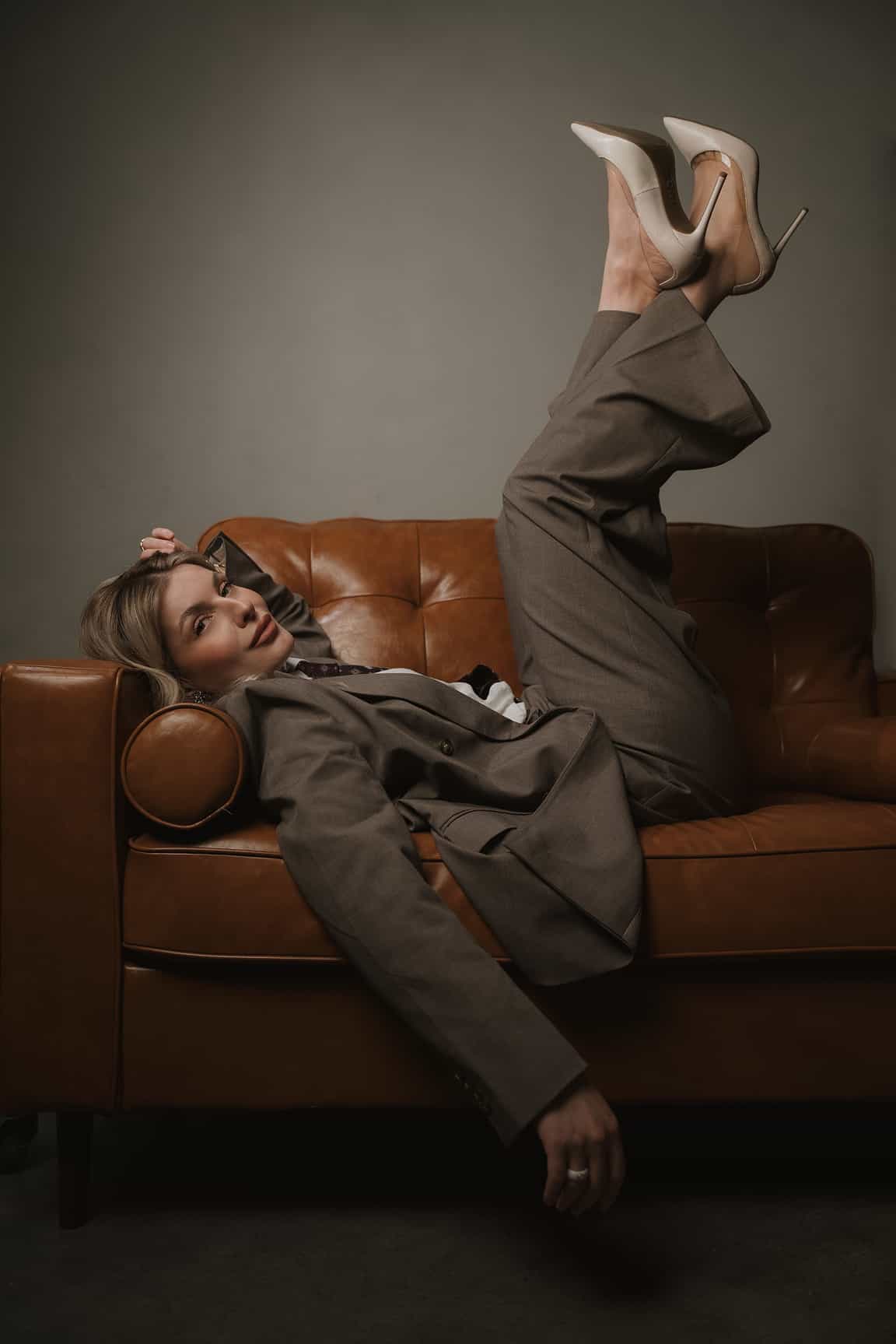 Creative studio portrait of a woman posing on a leather couch